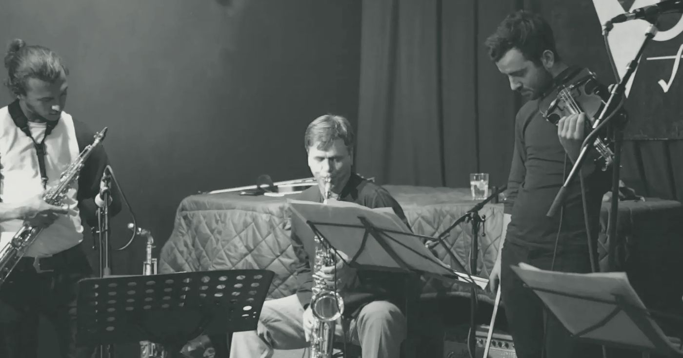 The trio on stage at the Vortex with a guest saxophonist seated at a music stand